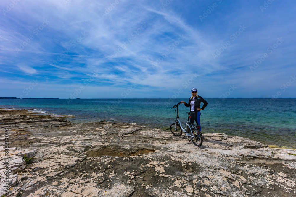 Fototapeta premium Cycling routes in Croatia woman in helmet riding electric bike on Adriatic Sea e-bike
