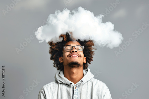 A man with glasses and dreadlocks is smiling and has a cloud on his head. Concept of happiness and lightheartedness photo