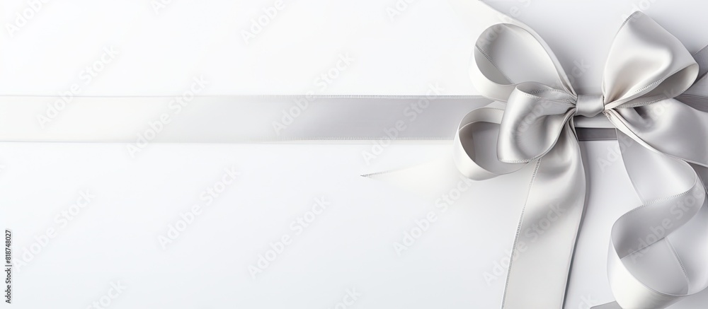 A silver silk ribbon featuring a lovely bow is showcased on a white background in this captivating copy space image A silver silk ribbon featuring a lovely bow is showcased on a white background in this captivating copy space image