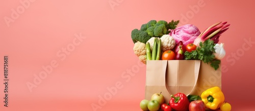 Copy space image featuring a pink background adorned with a variety of vegetables and fruits in a paper bag photo