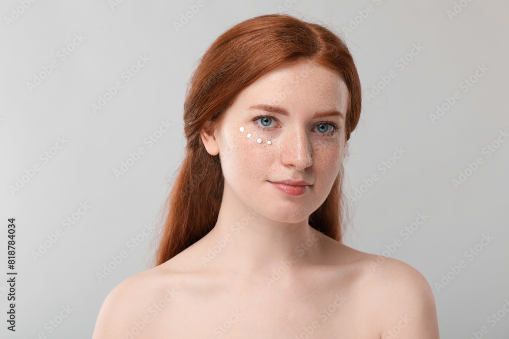 Beautiful woman with freckles and cream on her face against grey background Beautiful woman with freckles and cream on her face against grey background