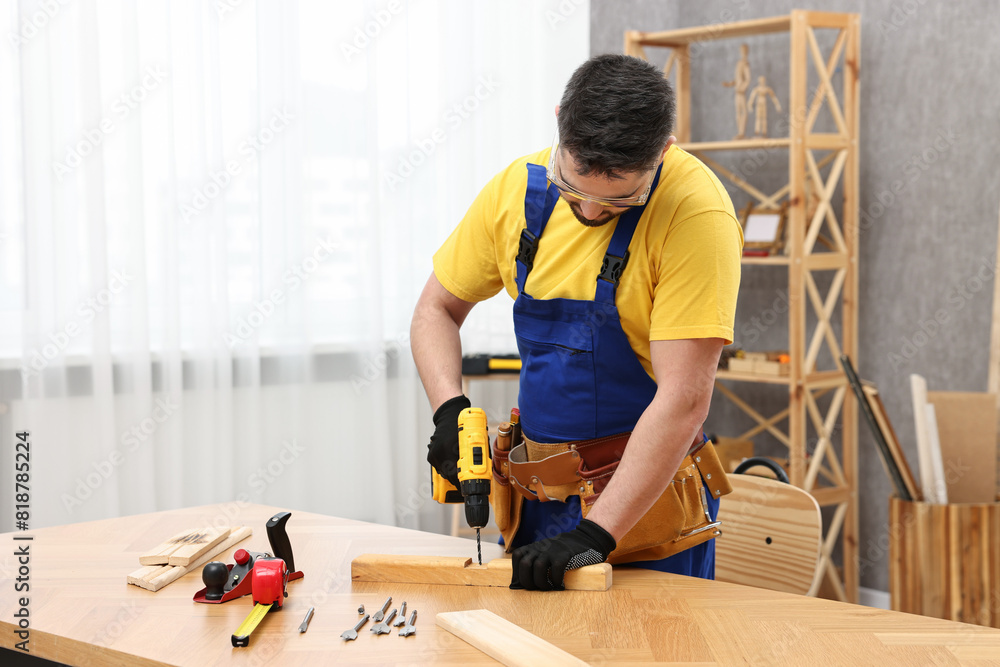 Young worker using electric drill at table in workshop Young worker using electric drill at table in workshop