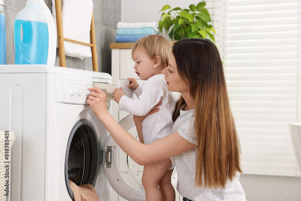 Mother with her daughter washing baby clothes in bathroom Mother with her daughter washing baby clothes in bathroom