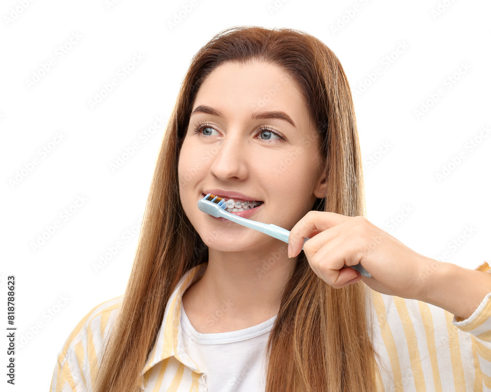 Smiling woman with dental braces cleaning teeth on white background Smiling woman with dental braces cleaning teeth on white background