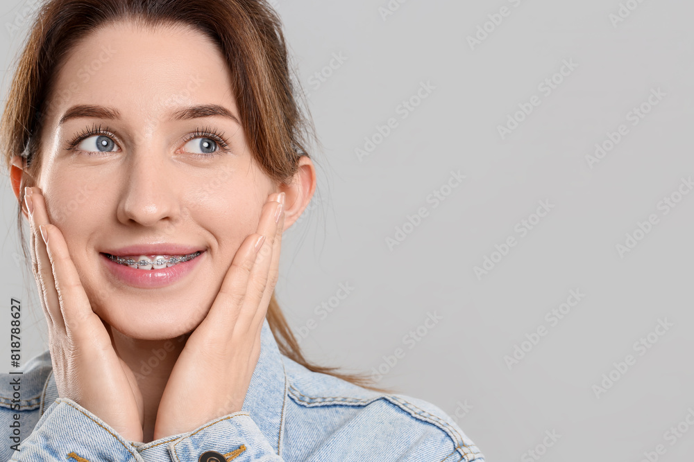 Portrait of smiling woman with dental braces on grey background. Space for text Portrait of smiling woman with dental braces on grey background. Space for text