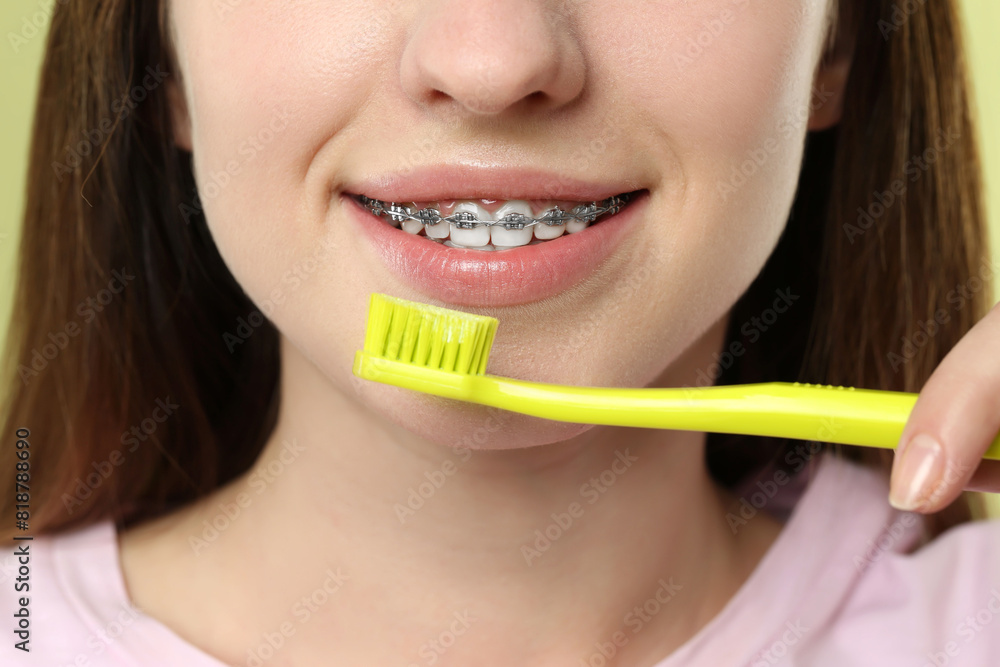 Smiling woman with dental braces cleaning teeth, closeup Smiling woman with dental braces cleaning teeth, closeup