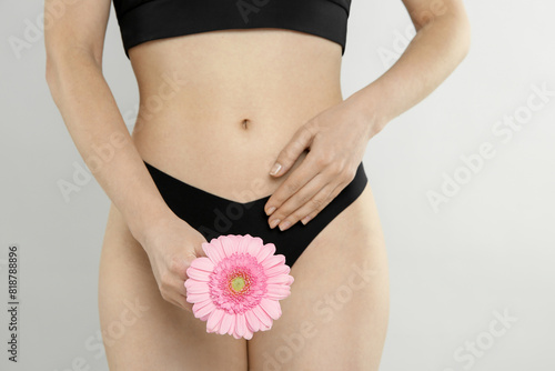 Gynecology. Woman in underwear with gerbera flower on light background, closeup