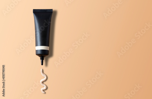 Tube of cosmetic product with a sample nearby on a brown background with copy space. Skin care products, hand cream, facial cleanser.