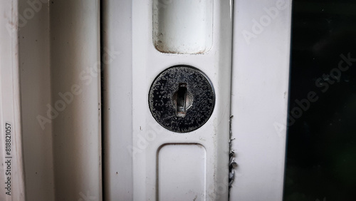 Close-Up of a Weathered Door Lock on a White Frame, Detailed view of a weathered, slightly rusted door lock set in a white frame, highlighting age and use photo