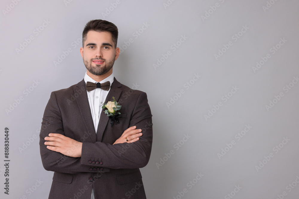 Handsome young groom with boutonniere on light grey background, space for text. Wedding accessory Handsome young groom with boutonniere on light grey background, space for text. Wedding accessory