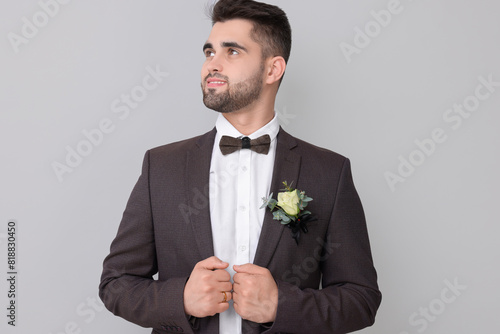 Handsome young groom with boutonniere on light grey background. Wedding accessory