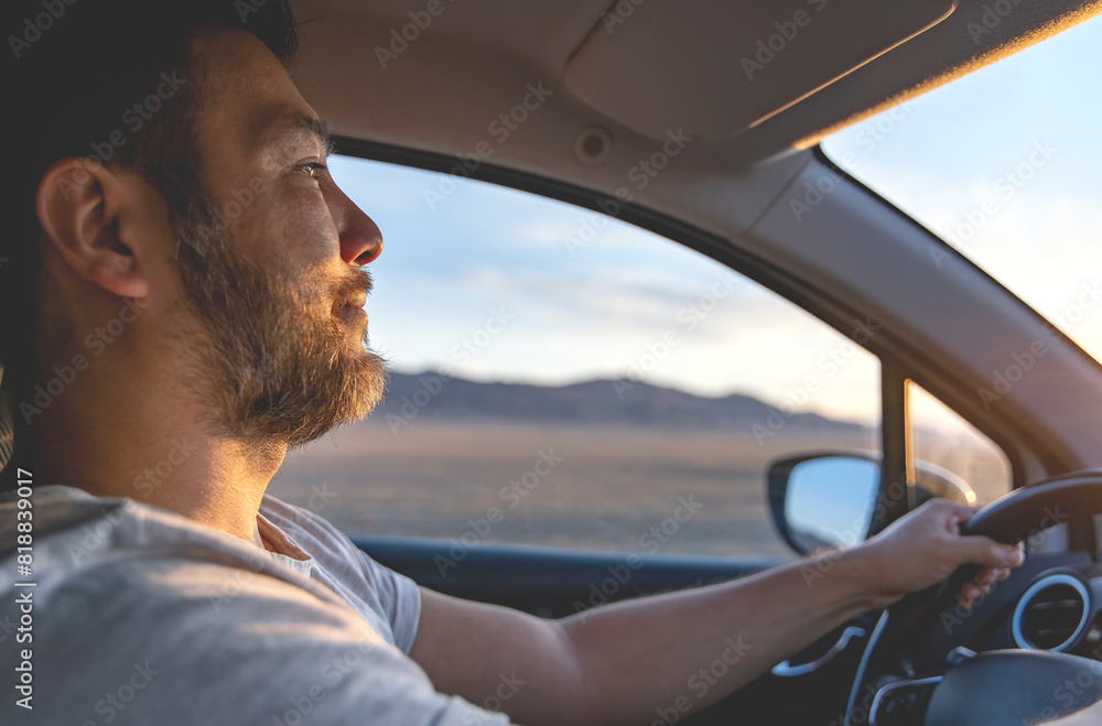 Man driving a car. Beautiful nature and mountains at sunset in side window.