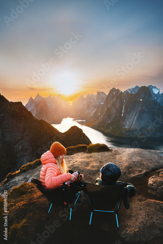 Family picnic in mountains mother and child drinking hot chocolate with thermos sitting in camping chairs travel summer vacations outdoor woman with kid hiking together in Lofoten islands Norway