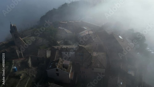 Ascending drone footage of Fiorenzuola di Focara village covered with dense fog at sunrise, Italy photo