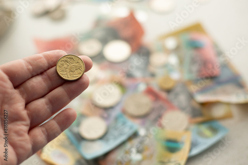 person holding an Australian one dollar coin with other money in the background photo