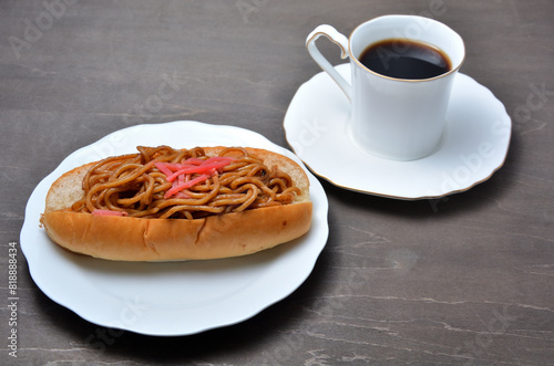 白い皿に乗ったおいしそうな焼きそばパンとコーヒー