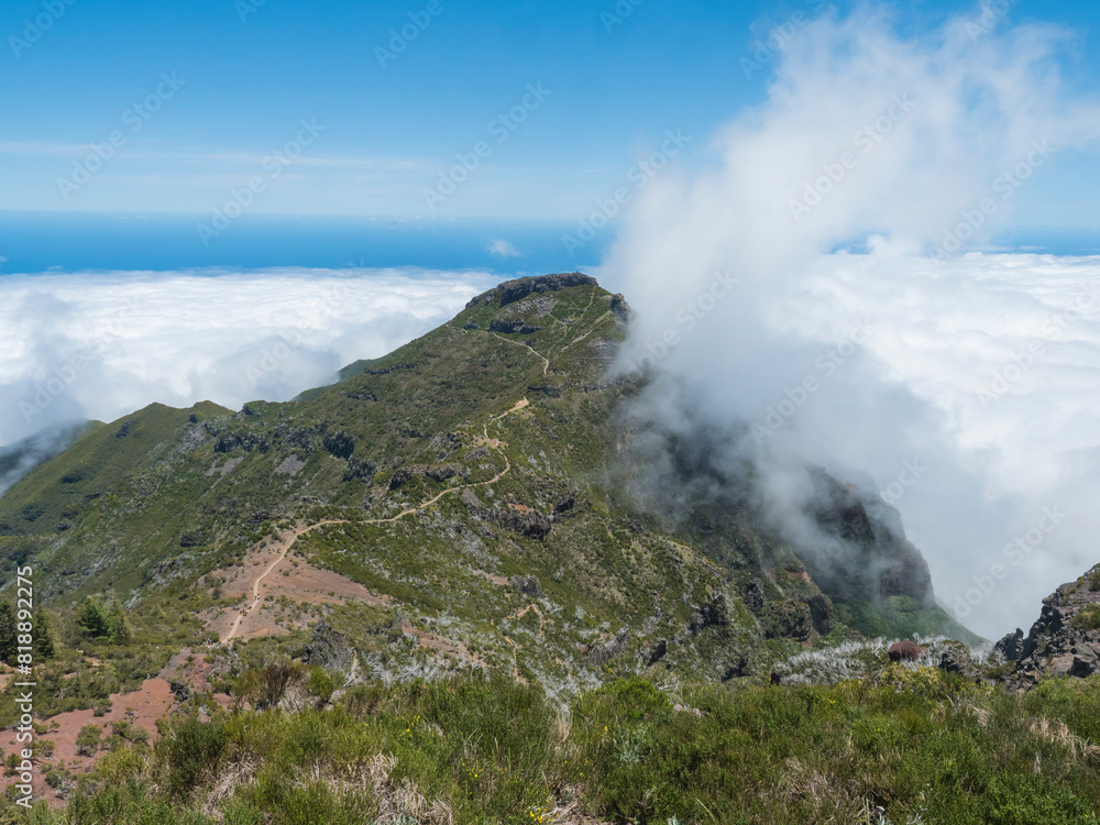 View from Pico Ruivo highest peak in the Madeira, Portugal. Green mountains, misty clouds and and atlantic ocean at Hiking trail PR1.2 from Achada do Teixeira to Pico Ruivo.