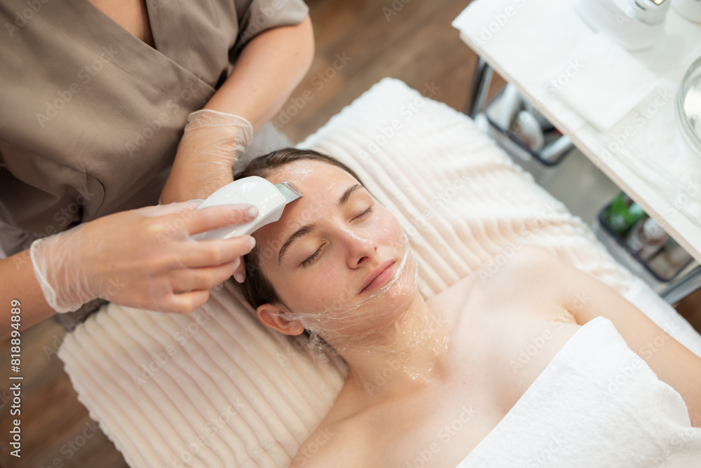 Young woman receiving cleansing therapy with a professional ultrasonic equipment in cosmetology office. Professional beauty procedure, caring about your skin and body concept Young woman receiving cleansing therapy with a professional ultrasonic equipment in cosmetology office. Professional beauty procedure, caring about your skin and body concept
