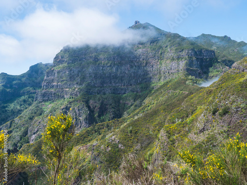 View of green hills  mountain landscape in clouds at blue sky. and lush vegetation at hiking trail PR12 to Pico Grande one of the highest peaks in the Madeira  Portugal