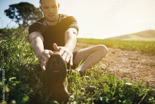 Runner, grass or man stretching legs for training, exercise or fitness workout in countryside nature. Muscle warm up, healthy or sports athlete ready to start practice for wellness, body or running photo