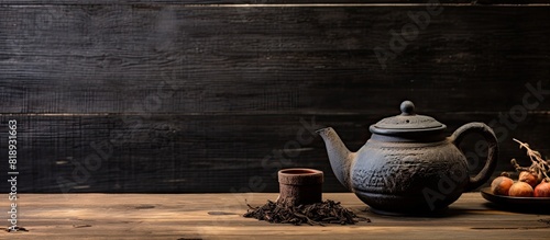A copy space image with a black tea clay kettle tea strainer and sugar on an antique wooden backdrop photo