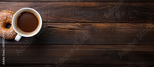 Copy space image of a donut paired with a cup of black coffee on a wooden background