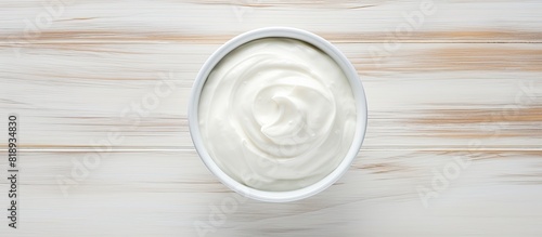 A top down view of a bowl of Greek yogurt rested on a white wooden surface with the perfect amount of space for additional images or text This captures the concept of Greek organic yogurt