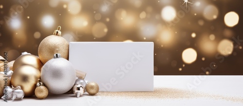 Copy space image of a Christmas themed postcard template with a mockup of a blank paper card an envelope a white present box and festive gold and silver ornaments The background is beige with Christm photo