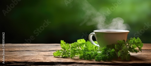 Copy space image of a steaming cup of tea and a bunch of fresh parsley placed on a rustic wooden surface