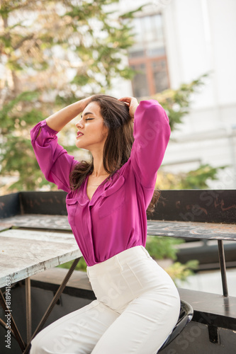 Obraz na płótnie Beautiful young brunette woman in a purple blouse and white pants posing outdoor. Portrait of a beautiful young brunette woman with long hair posing fashion w salonie