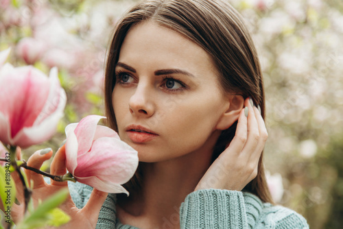 Spring portrait of young woman near blooming magnolia.