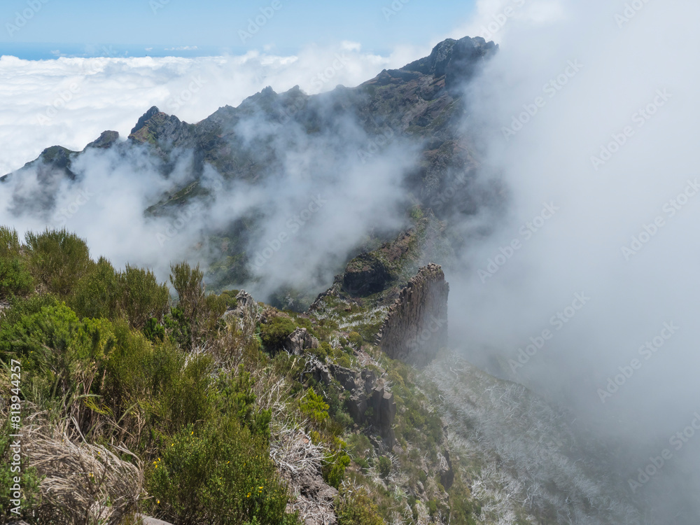 View from Pico Ruivo highest peak in the Madeira, Portugal. Green mountains, misty clouds and and atlantic ocean at Hiking trail PR1.2 from Achada do Teixeira to Pico Ruivo.