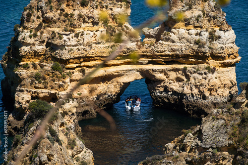 Ponta da Piedade near Lagos in Algarve, Portugal. Cliff rocks and tourist boat on sea. Praia Dona Ana, Estudantes beach. Sunny day. Point of Pity