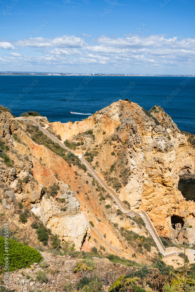 Ponta da Piedade near Lagos in Algarve, Portugal. Cliff rocks and tourist boat on sea. Praia Dona Ana, Estudantes beach. Sunny day. Point of Pity