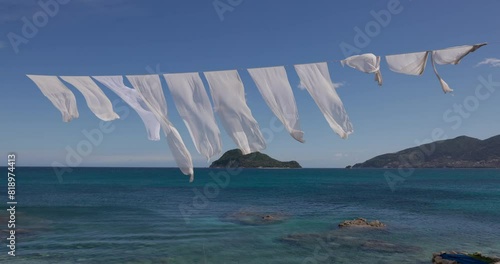 White sheets waving in the wind on Cameo Island with Turtle Island in the background, Zakynthos, Greece