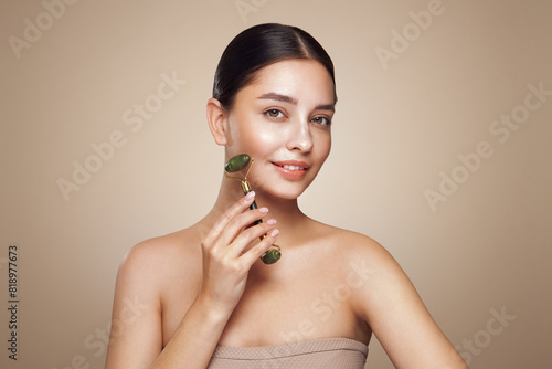 Photos Close up video of a young woman looking relaxed and smiling while using a natural jade face roller