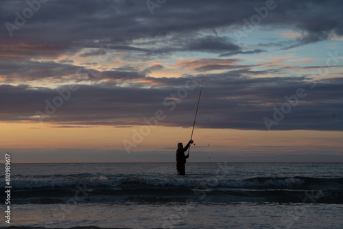 Pêcheur en surfcasting sur une plage de Bretagne en soirée - France