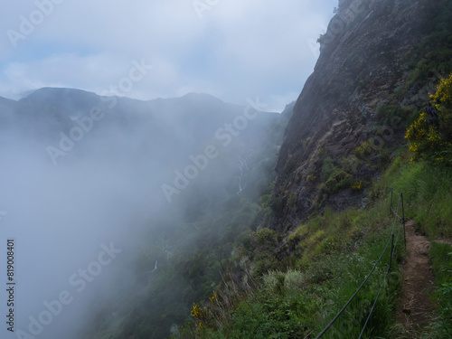 footpath in green grassy foggy misty mountain walls at hiking trail PR12 to Pico Grande one of the highest peaks in the Madeira, Portugal © Kristyna