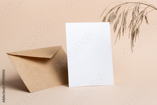 Blank greeting card mockup with dry grass decor and envelope on beige background
