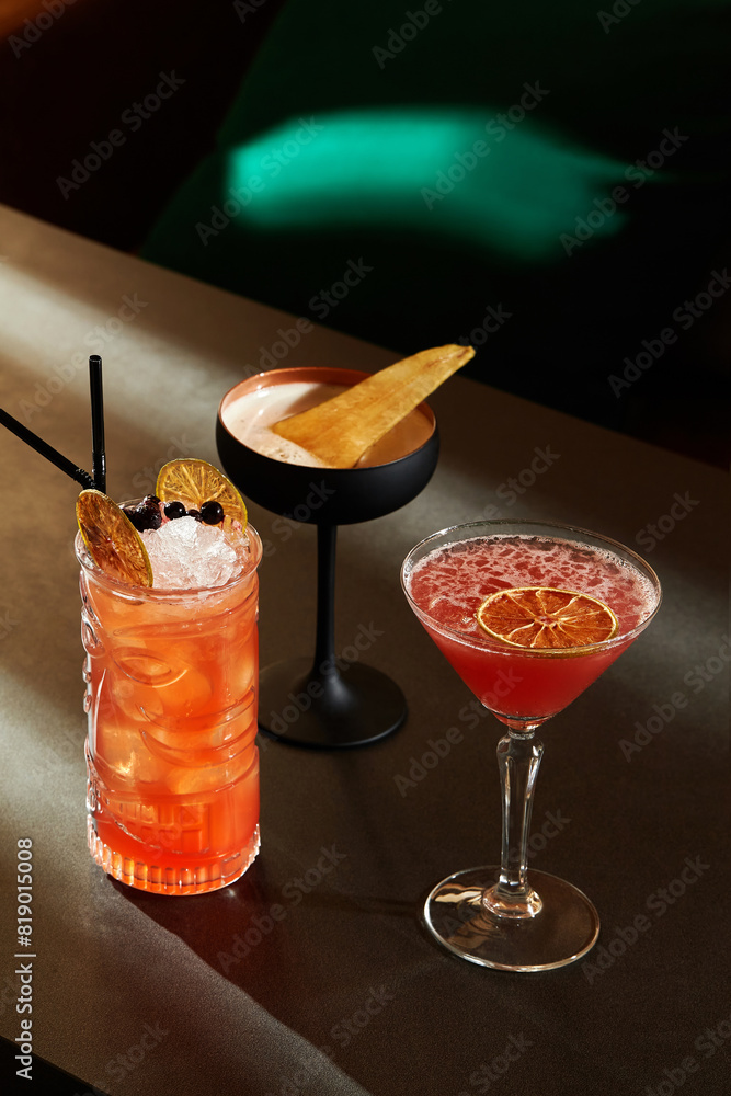 Trio of exquisite refreshing light cocktails with berries and citrus on bar