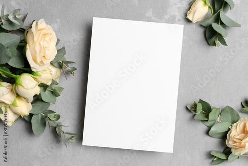 Wedding invitation card mockup with roses flowers on grey background, flat lay with copy space