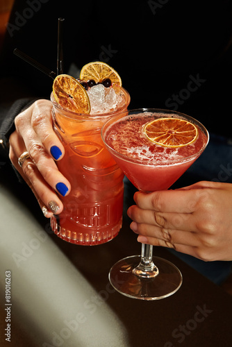 Female hands with glasses of beautifully garnished light cocktails