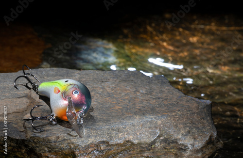 Artificial fishing bait next to a lake's water