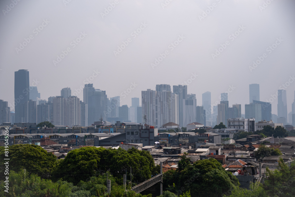 View of the residential area and skyscrapers in the background under the pollution sky in Jakarta. View of the residential area and skyscrapers in the background under the pollution sky in Jakarta.