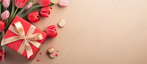 Red tulips and gift box in heart shape with red bow on pastel paper background Beautiful spring floral layout Greeting card for Valentine s women s or mother s day Flat lay top view copy space © Gular