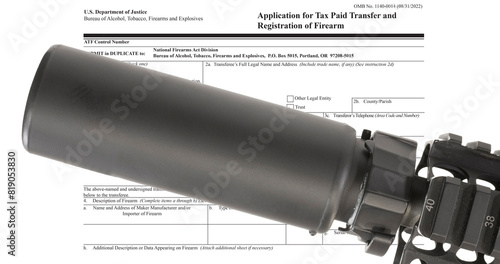 ATF tax form in the public domain behind a silencer mounted on an AR-15