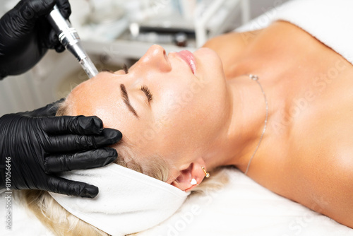 Microneedle RF lifting procedure. A cosmetologist performs a facial rejuvenation procedure on a woman. Hardware cosmetology.