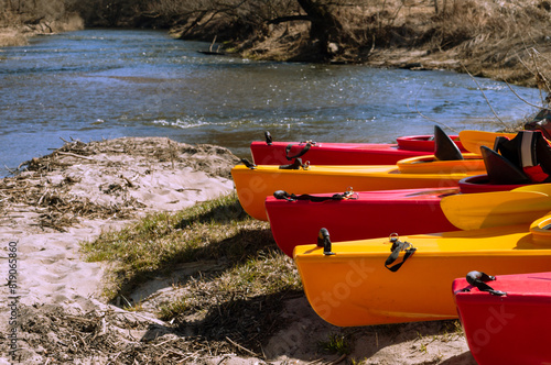 Kayak on the river bank. Active pastime of the weekend. Sports tourism. Kayak rafting in the spring. Kayaks made of yellow and red plastic.