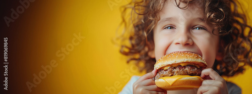 Little Girl Eating Hamburger on Yellow Background