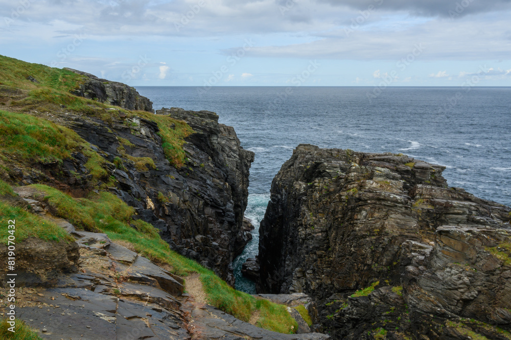 Rocky Cliff Overlooks Ocean on Cloudy Day